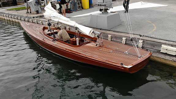 Holzboot im Wasser neben Kran